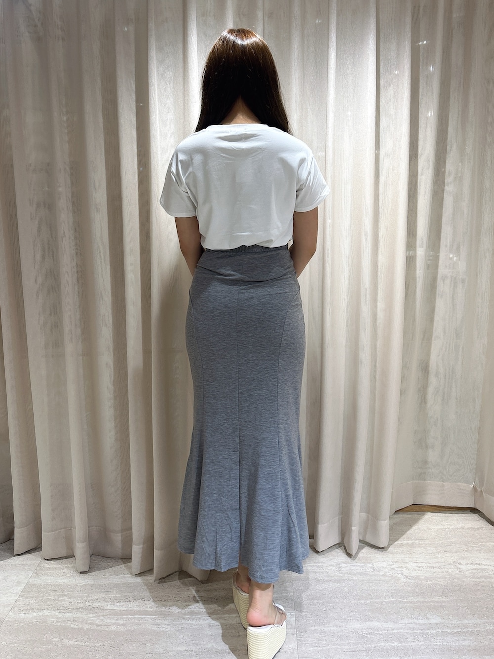 グレー系のスカート、ホワイト系のTシャツ/カットソー、ホワイト系のサンダルを着用したレディースの夏コーディネートの4枚目の写真