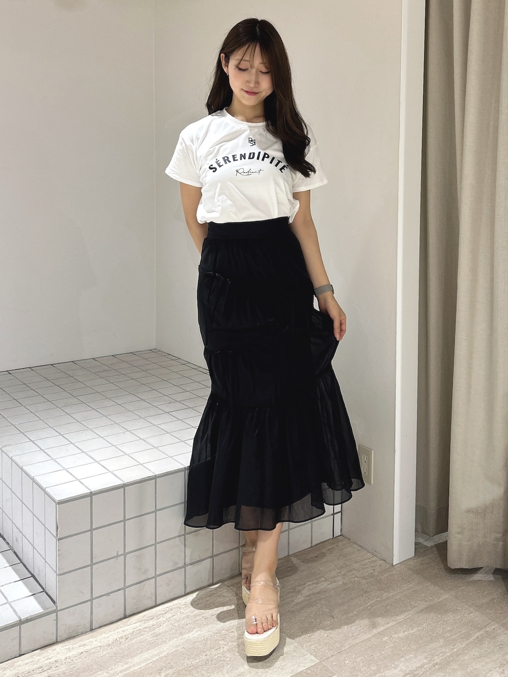 ブラック系のスカート、ホワイト系のTシャツ/カットソー、ホワイト系のサンダルを着用したレディースの夏コーディネートの2枚目の写真