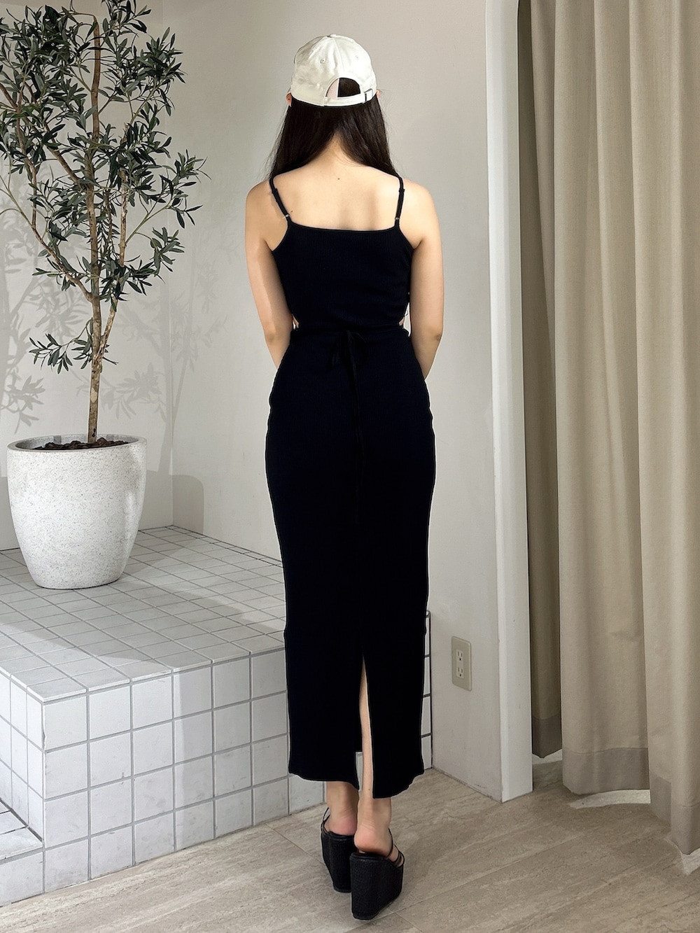 ブラック系のワンピース、ブラック系のサンダル、ベージュ系のキャップを着用したレディースの夏コーディネートの5枚目の写真