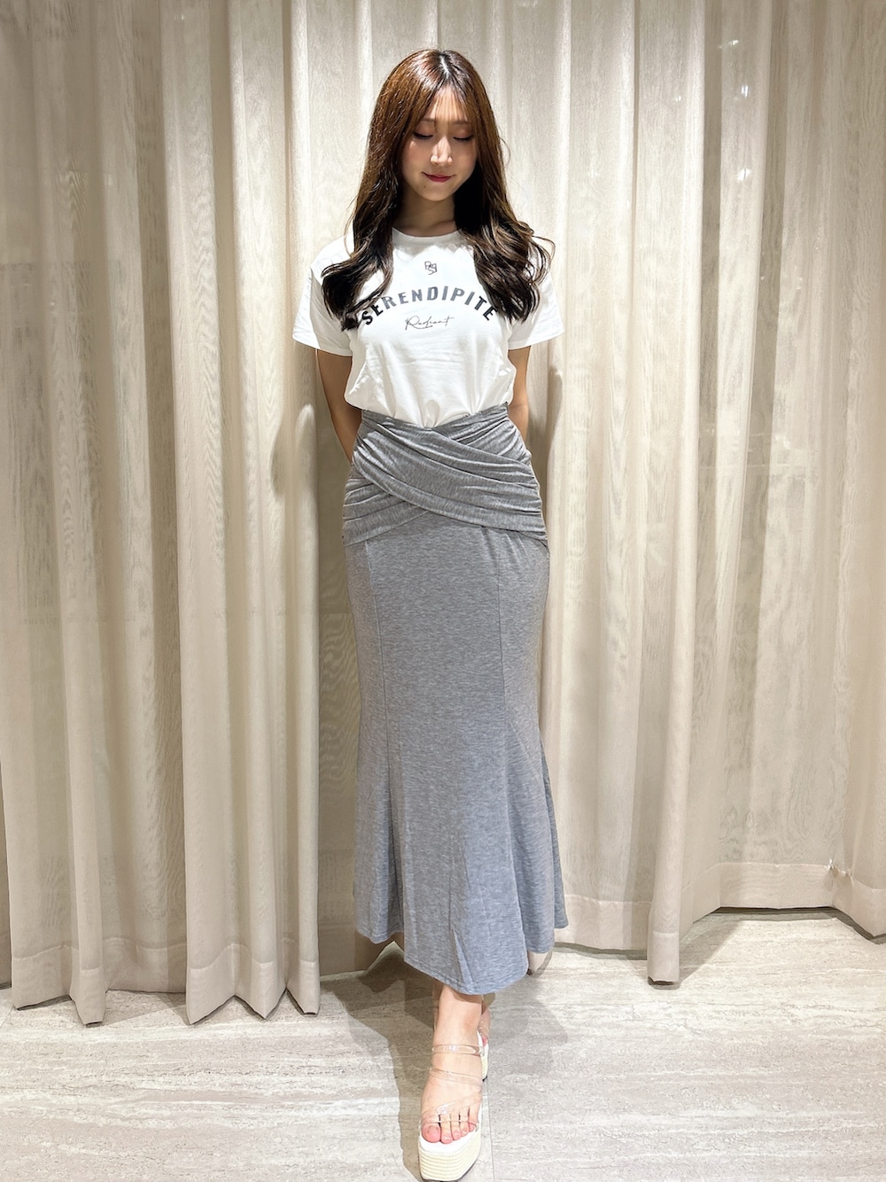 グレー系のスカート、ホワイト系のTシャツ/カットソー、ホワイト系のサンダルを着用したレディースの夏コーディネートの2枚目の写真