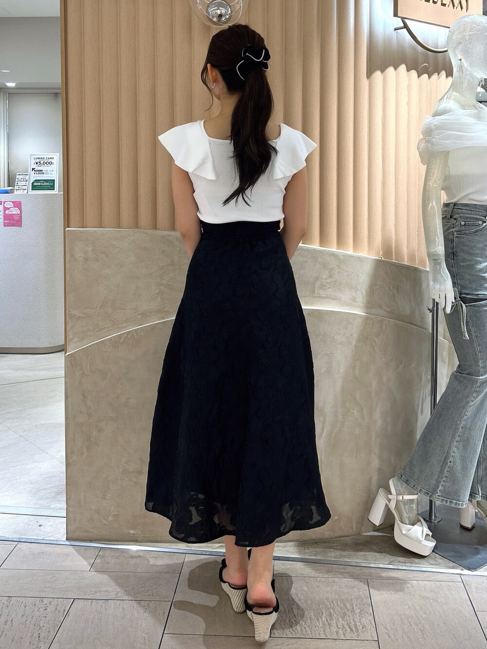 ブラック系のスカート、ホワイト系のニット/セーターを着用したレディースの夏コーディネートの4枚目の写真