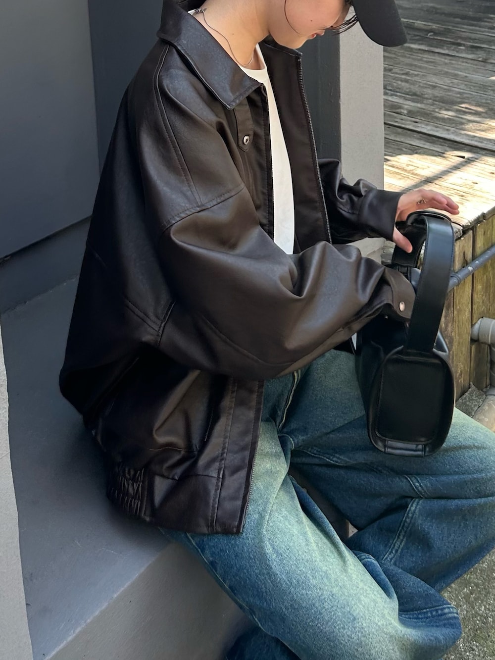 ブラック系のブルゾン、ホワイト系のTシャツ/カットソー、ブルー系のデニムパンツを着用したレディースの夏コーディネートの3枚目の写真