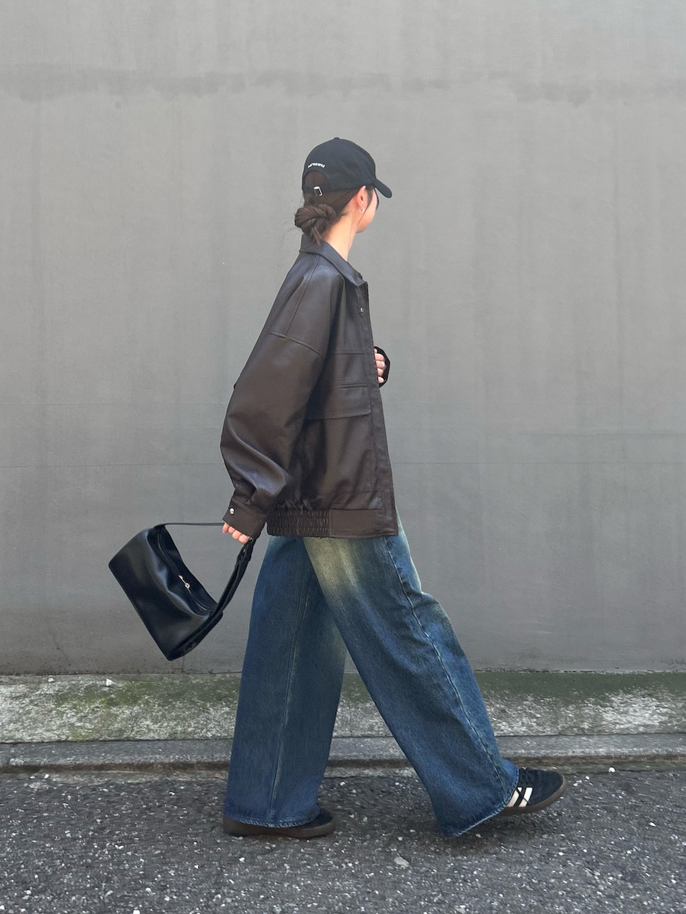 ブラック系のブルゾン、ホワイト系のTシャツ/カットソー、ブルー系のデニムパンツを着用したレディースの夏コーディネートの2枚目の写真