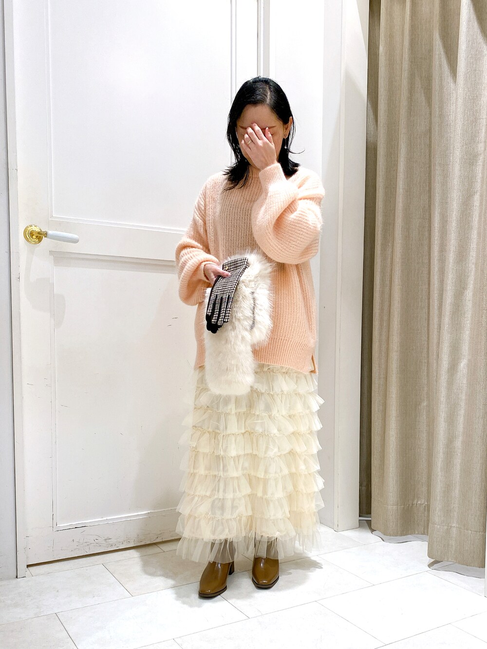 ピンク系のニット/セーター、ホワイト系のジャケット/アウター、ホワイト系のスカートを着用したレディースの冬コーディネートの2枚目の写真