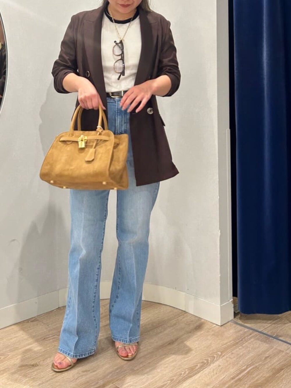 ブルー系のデニムパンツ、イエロー系のトートバッグ、ブラウン系のテーラードジャケットを着用したレディースの夏コーディネートの2枚目の写真