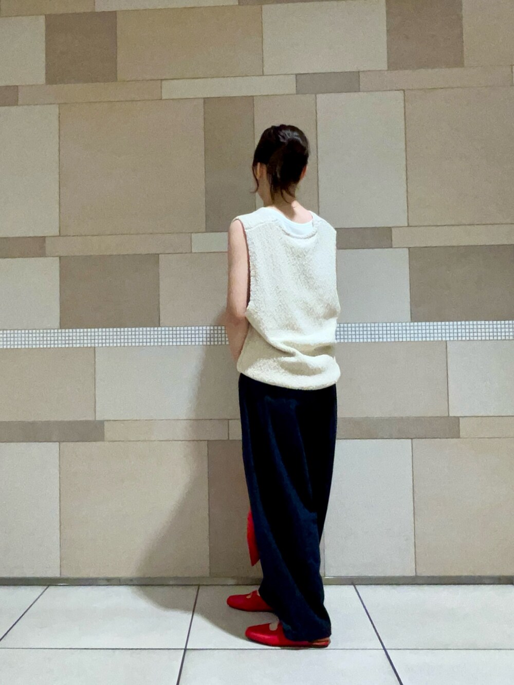 ホワイト系のベスト、ブルー系のデニムパンツ、レッド系のサンダルを着用したレディースの夏コーディネートの3枚目の写真