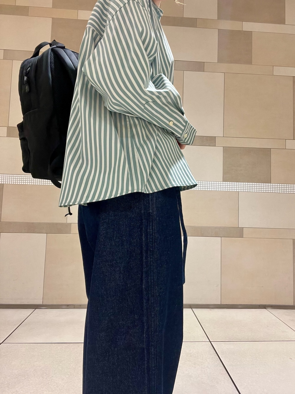 ブルー系のデニムパンツ、ブラック系のバックパック/リュック、ブラック系のサンダルを着用したレディースの秋コーディネートの4枚目の写真