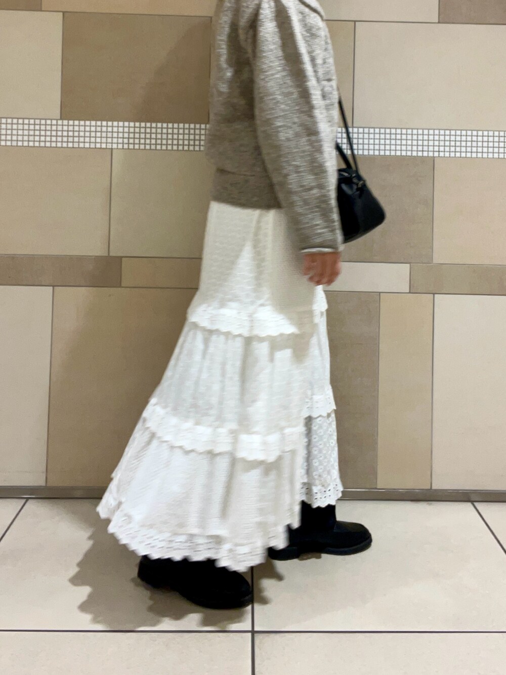 グレー系のカーディガン/ボレロ、ブラック系のハンドバッグ、ホワイト系のスカートを着用したレディースの秋コーディネートの3枚目の写真