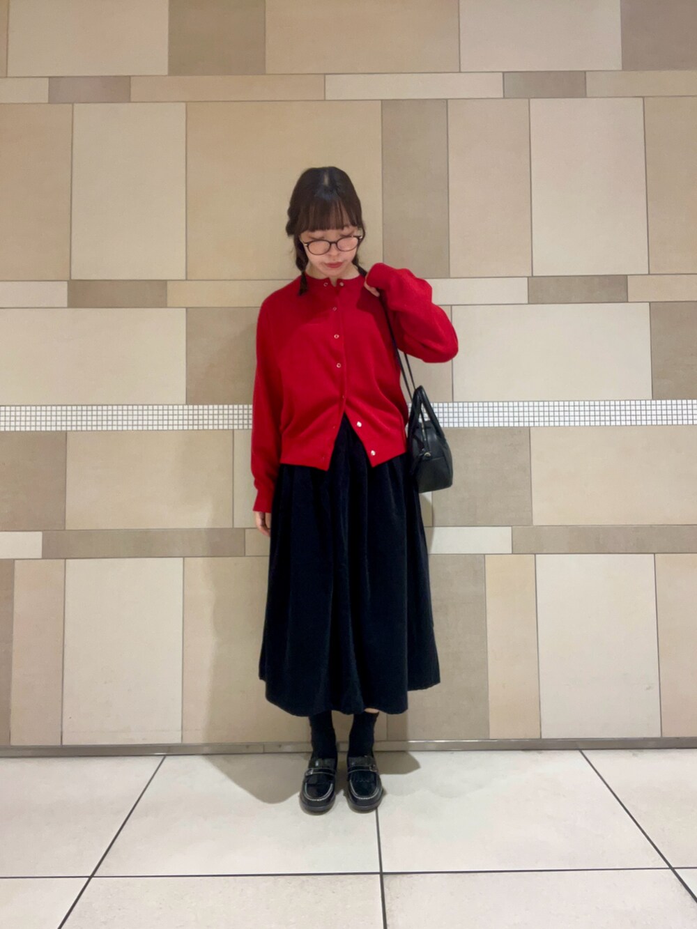 レッド系のカーディガン/ボレロ、グレー系のスカート、ブラック系のローファーを着用したレディースの秋コーディネートの2枚目の写真