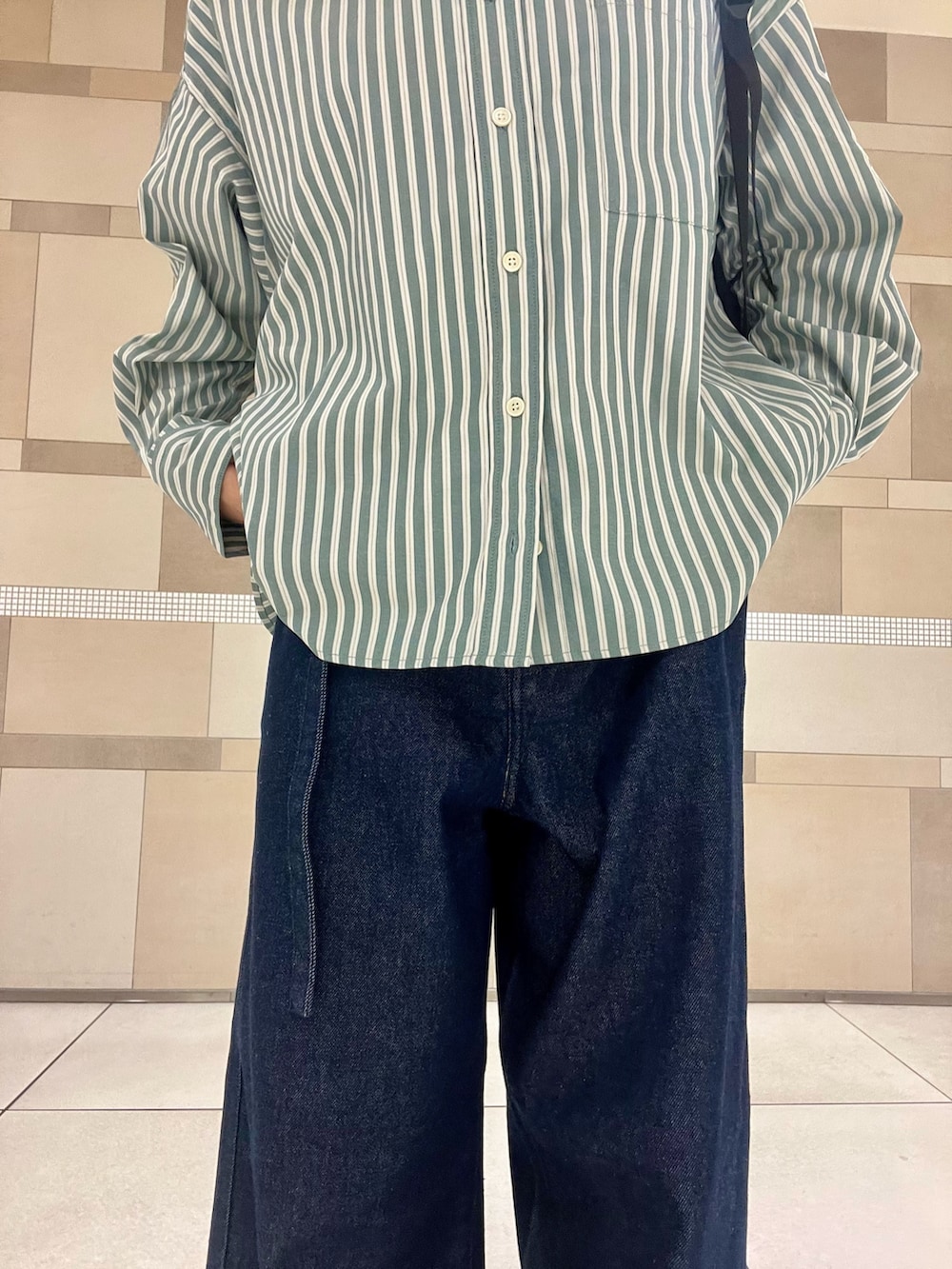 ブルー系のデニムパンツ、ブラック系のバックパック/リュック、ブラック系のサンダルを着用したレディースの秋コーディネートの3枚目の写真