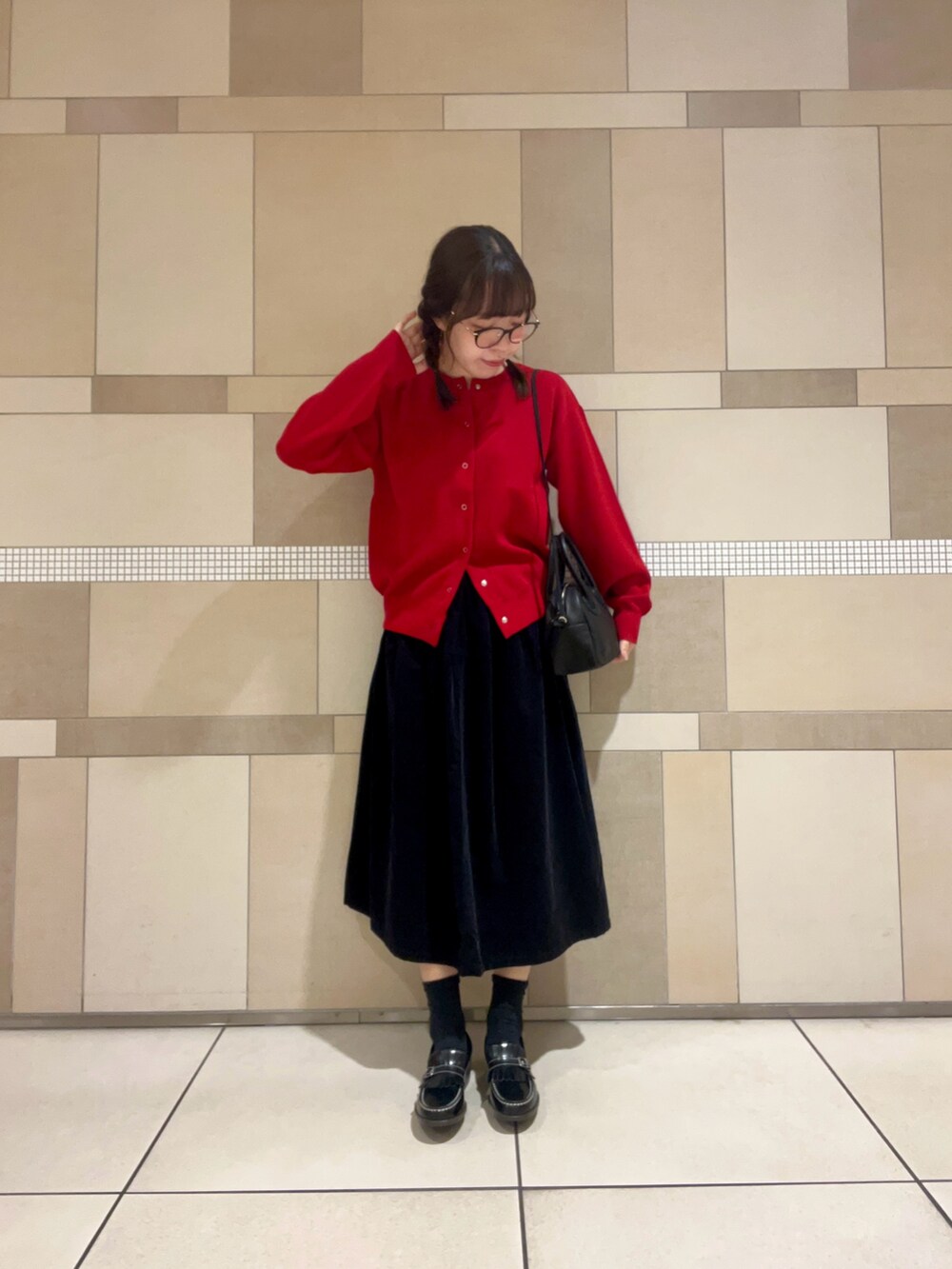 レッド系のカーディガン/ボレロ、グレー系のスカート、ブラック系のローファーを着用したレディースの秋コーディネートの3枚目の写真