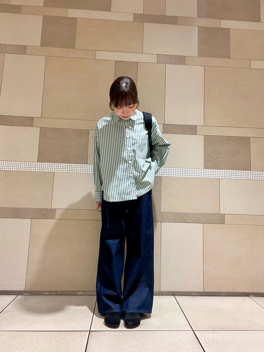 ブルー系のデニムパンツ、ブラック系のバックパック/リュック、ブラック系のサンダルを着用したレディースの秋コーディネートの2枚目の写真