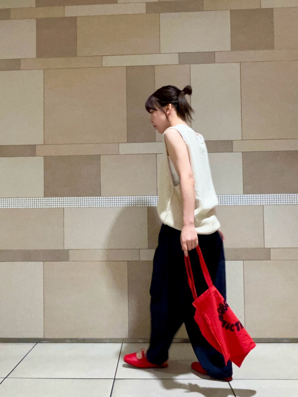 ホワイト系のベスト、ブルー系のデニムパンツ、レッド系のサンダルを着用したレディースの夏コーディネートの2枚目の写真