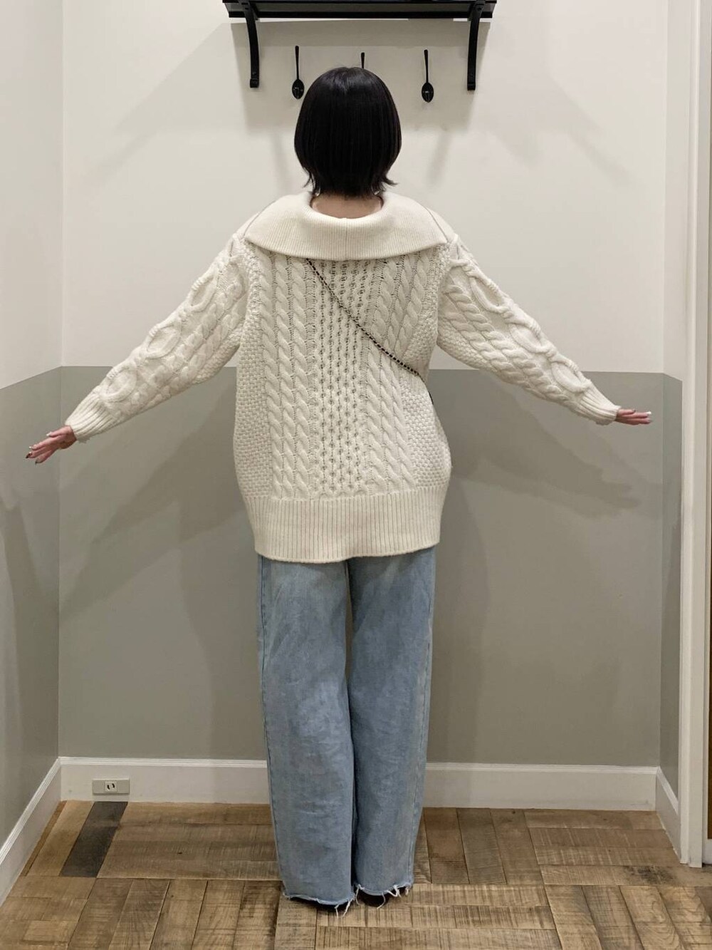 ブルー系のショルダーバッグ、ホワイト系のニット/セーター、ブルー系のデニムパンツを着用したレディースの冬コーディネートの4枚目の写真