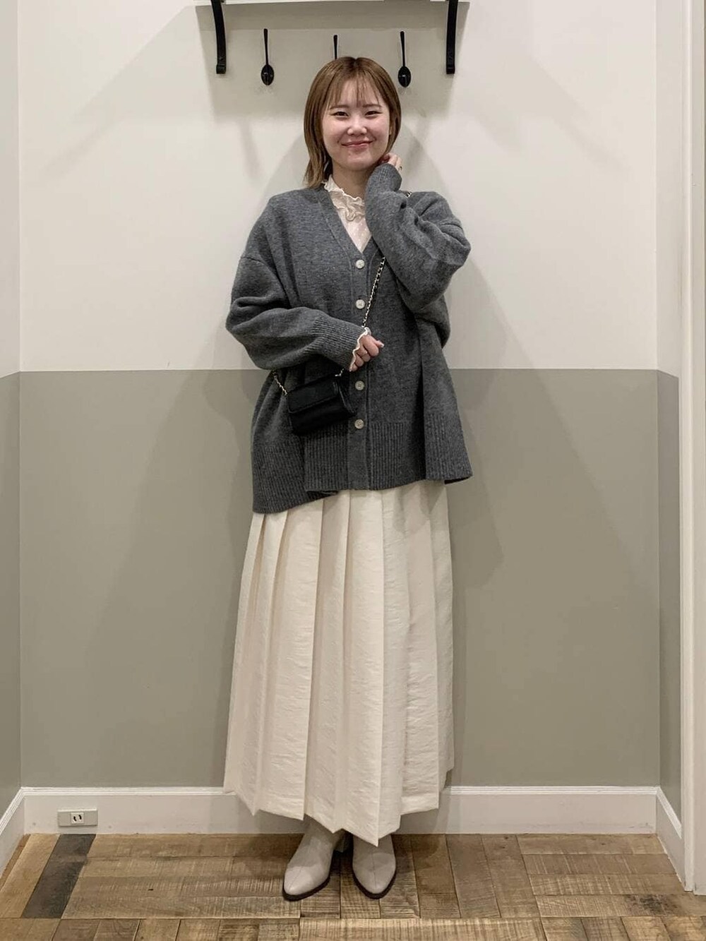 グレー系のカーディガン/ボレロ、ベージュ系のブーツ、ホワイト系のTシャツ/カットソーを着用したレディースの冬コーディネートの2枚目の写真