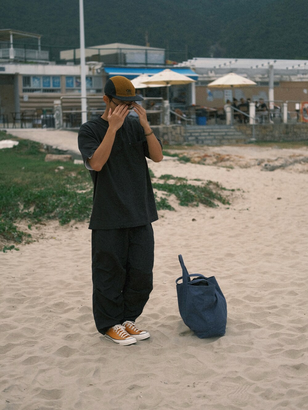 イエロー系のシューズ、オレンジ系の帽子を着用したメンズの春コーディネートの3枚目の写真