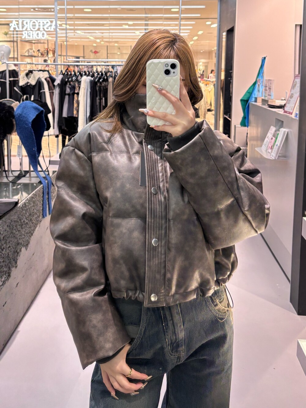 ホワイト系のニット/セーター、ブラウン系のダウンジャケット/コート、ブルー系のデニムパンツを着用したレディースの冬コーディネートの4枚目の写真