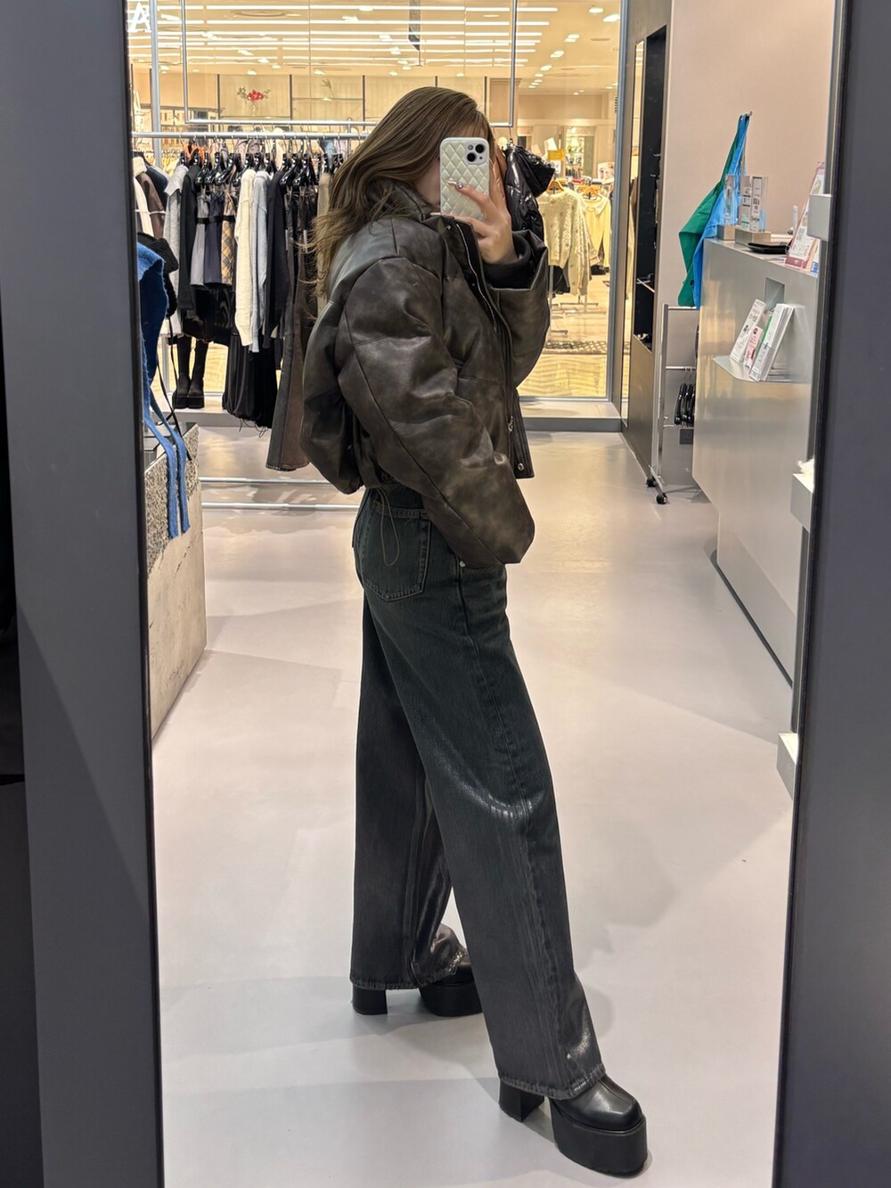 ホワイト系のニット/セーター、ブラウン系のダウンジャケット/コート、ブルー系のデニムパンツを着用したレディースの冬コーディネートの2枚目の写真