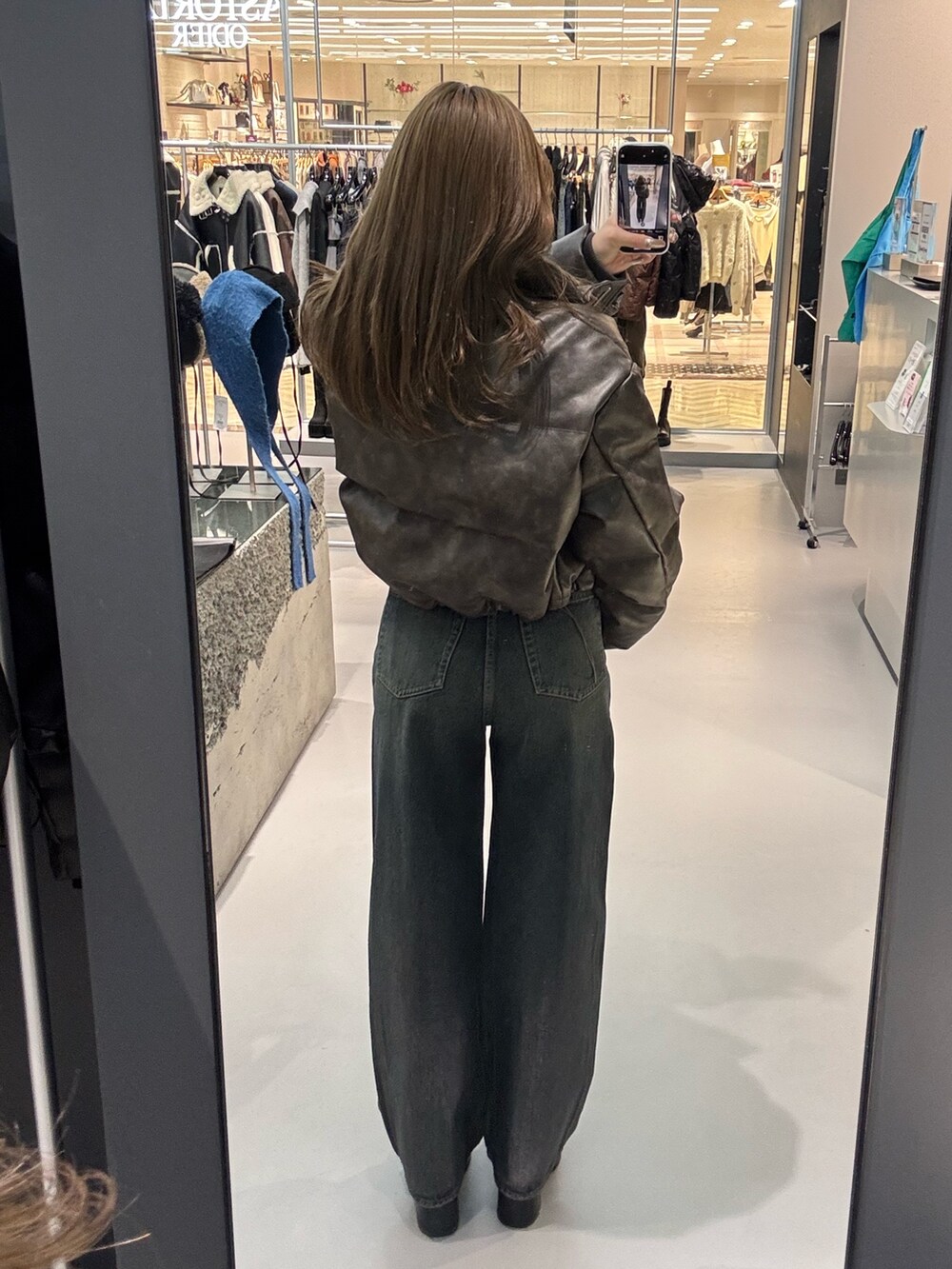 ホワイト系のニット/セーター、ブラウン系のダウンジャケット/コート、ブルー系のデニムパンツを着用したレディースの冬コーディネートの3枚目の写真