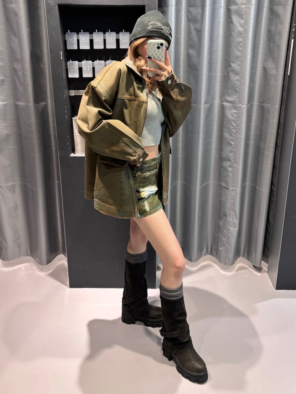 グレー系のニット/セーター、ブラウン系のブルゾン、ブラウン系のスカートを着用したレディースの冬コーディネートの2枚目の写真