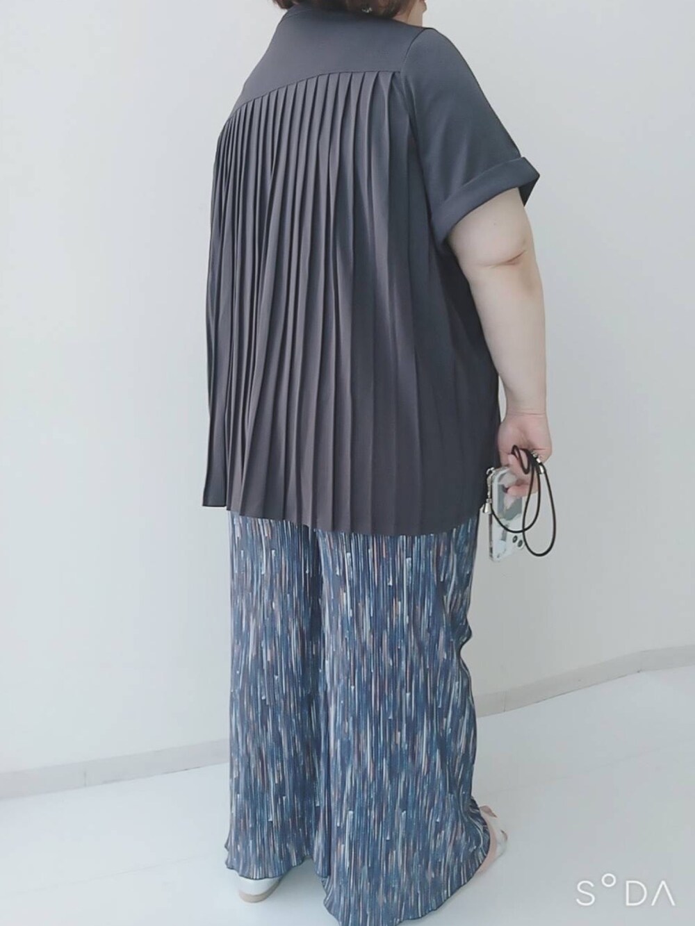 グレー系のチュニック、ブルー系のパンツ、シルバー系のサンダルを着用したレディースの夏コーディネートの2枚目の写真