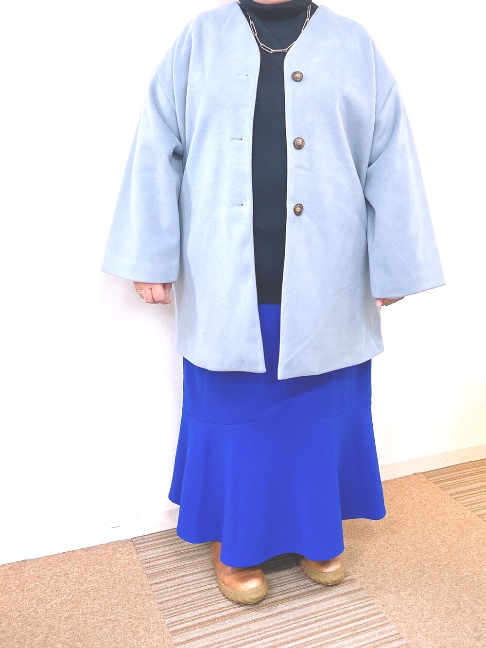 ブルー系のスカート、ブルー系のノーカラーコート、ブラック系のニット/セーターを着用したレディースの秋コーディネートの2枚目の写真