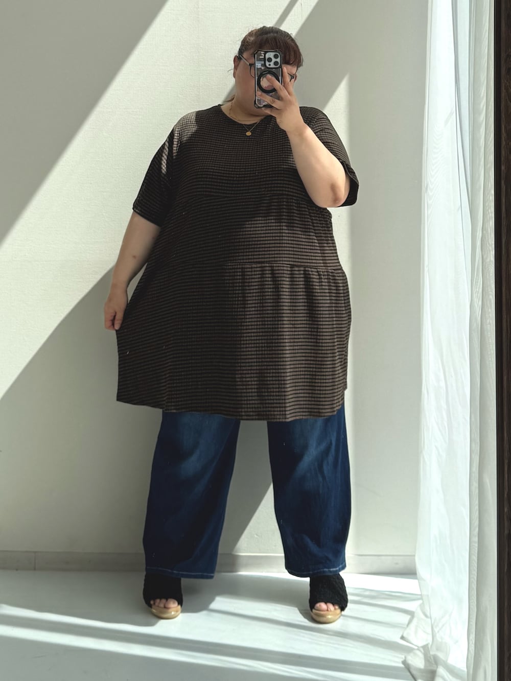 ブルー系のパンツ、ブラック系のサンダル、ブラウン系のチュニックを着用したレディースの春コーディネートの2枚目の写真