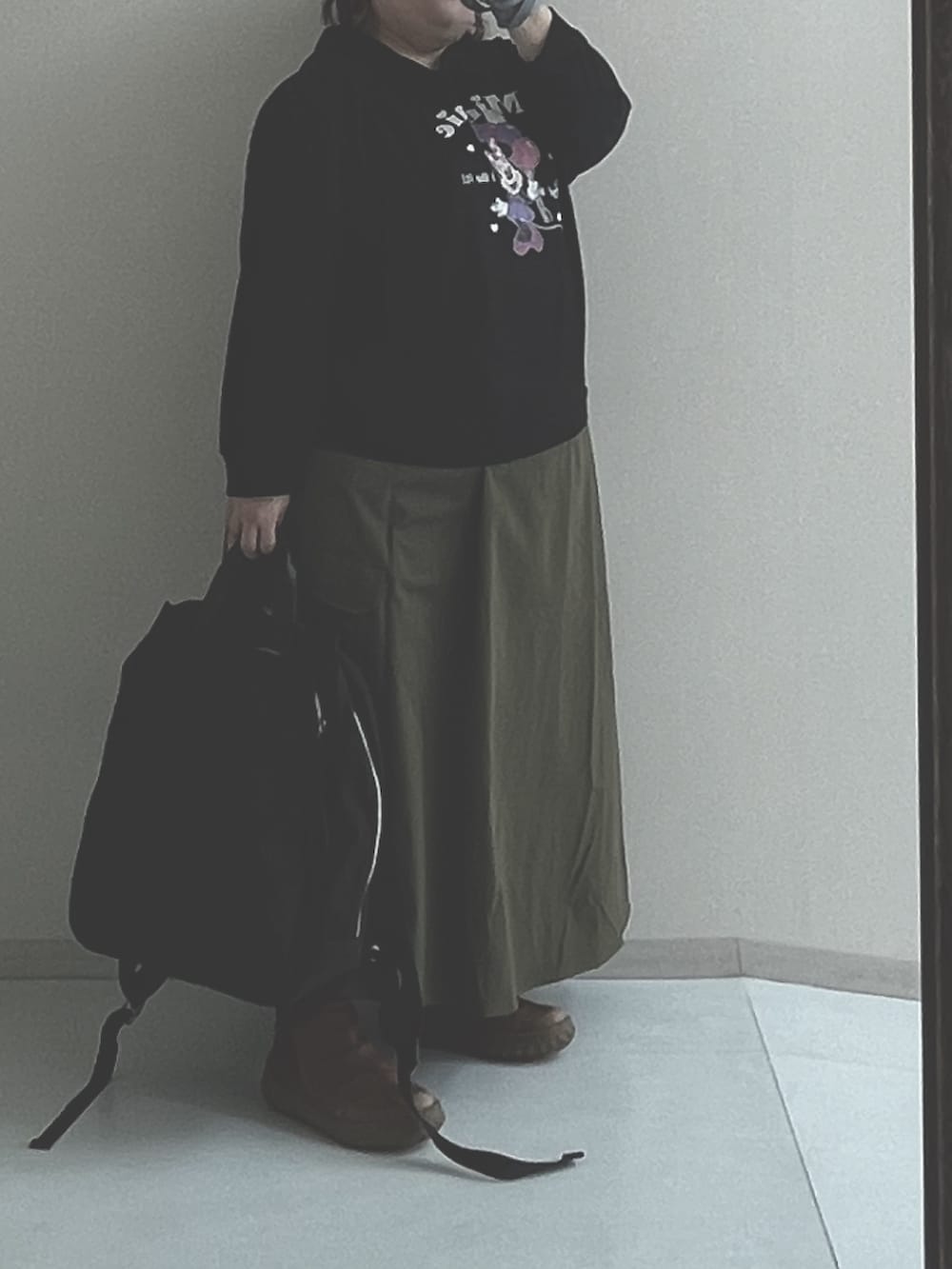 グリーン系のスカート、ブラック系のスウェット、ブラック系のバックパック/リュックを着用したレディースの冬コーディネートの2枚目の写真