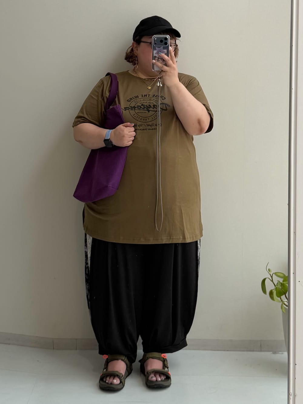 ブラック系のパンツ、ゴールド系のチュニック、ベージュ系のキャップを着用したレディースの夏コーディネートの3枚目の写真