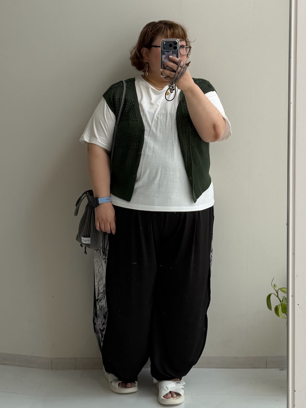 グリーン系のショルダーバッグ、ブラック系のパンツ、ブラック系のサンダルを着用したレディースの夏コーディネートの2枚目の写真