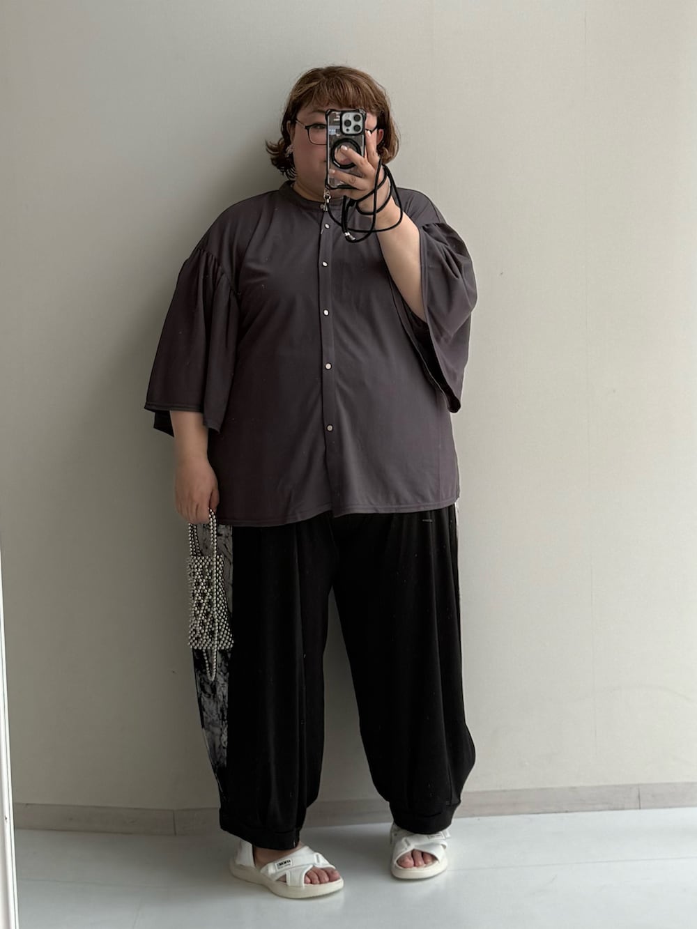 シルバー系のショルダーバッグ、ブラック系のパンツ、ホワイト系のサンダルを着用したレディースの夏コーディネートの2枚目の写真