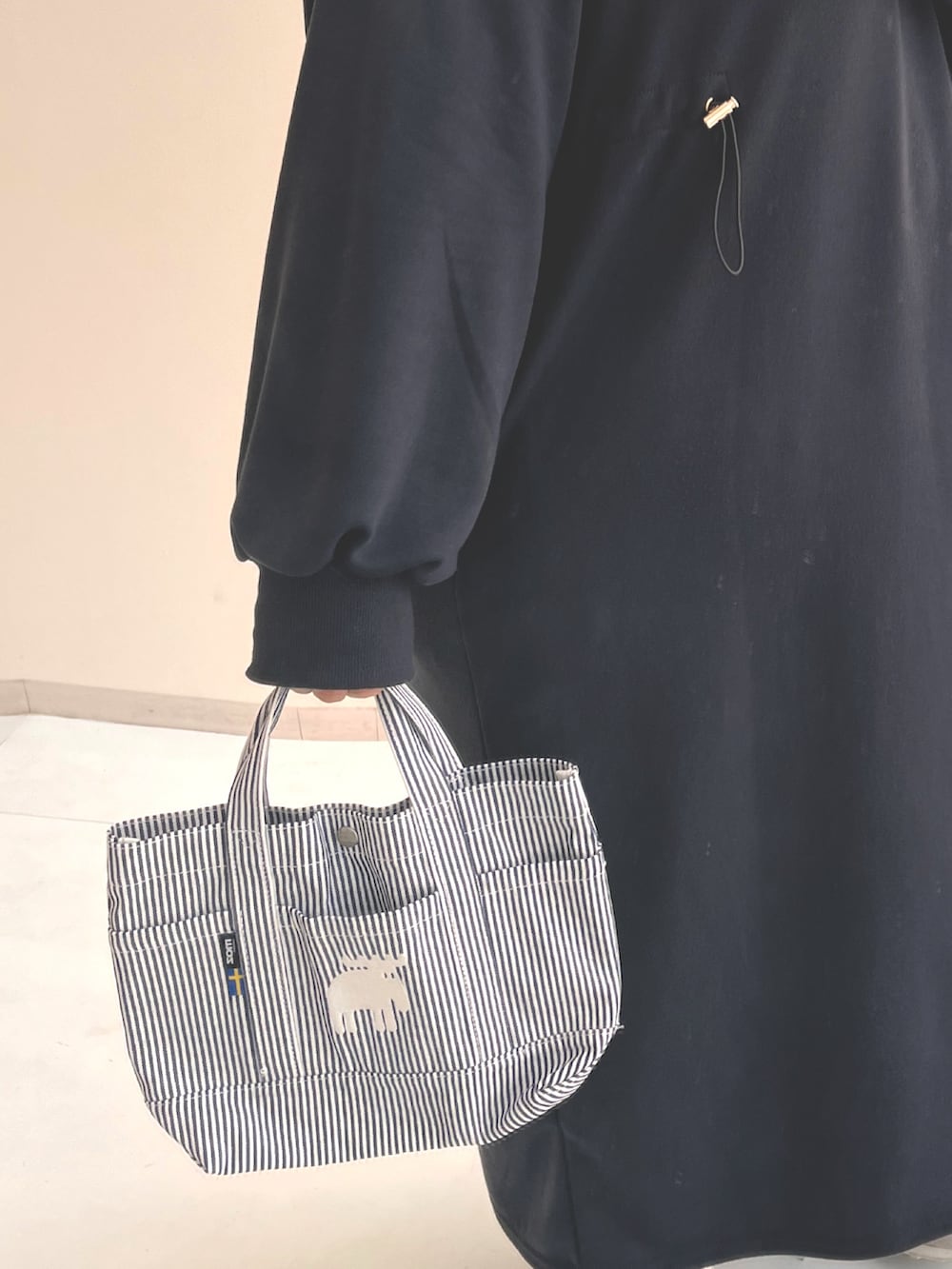 グレー系のワンピース、ベージュ系のスニーカー、ブルー系のトートバッグを着用したレディースの冬コーディネートの2枚目の写真