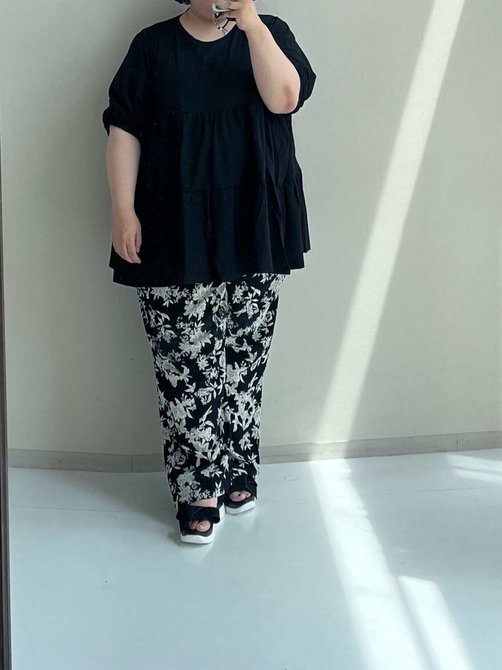 ブラック系のチュニック、ブラック系のパンツ、ブラック系のサンダルを着用したレディースの夏コーディネートの2枚目の写真