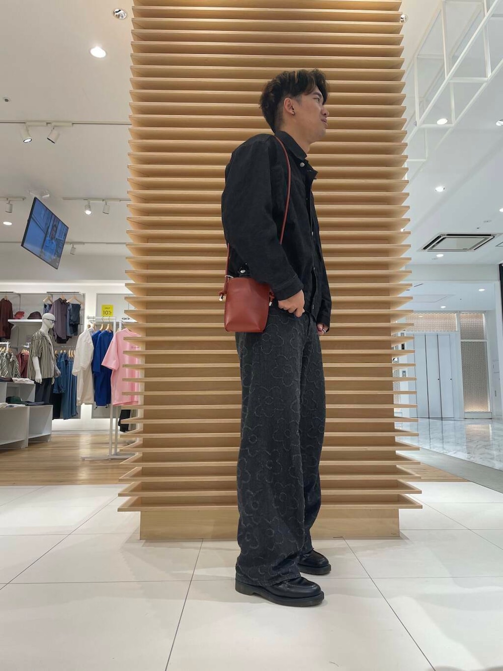 ブラック系のデニムパンツ、ブラック系のデニムジャケット、オレンジ系のショルダーバッグを着用したメンズの秋コーディネートの2枚目の写真