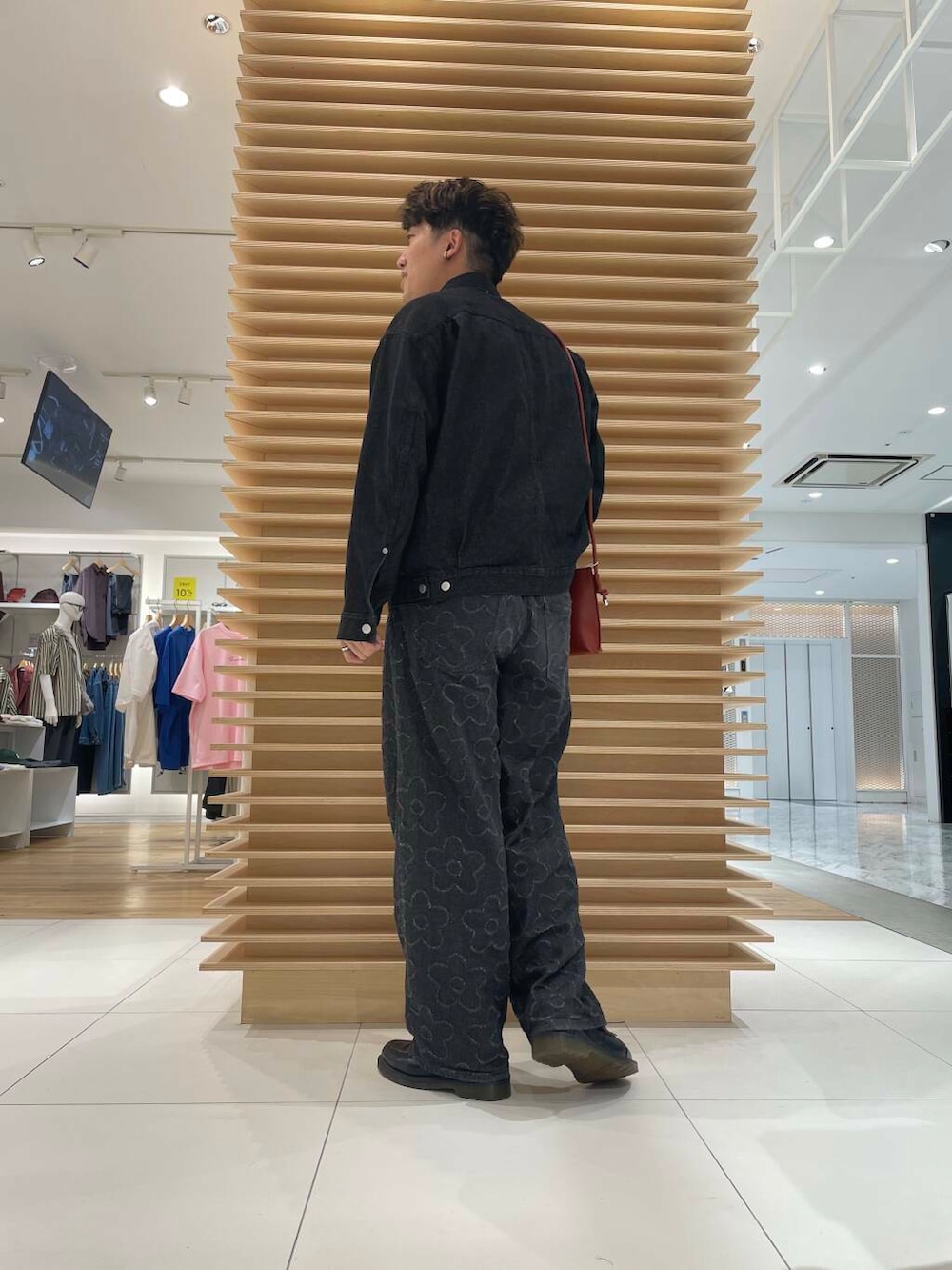 ブラック系のデニムパンツ、ブラック系のデニムジャケット、オレンジ系のショルダーバッグを着用したメンズの秋コーディネートの3枚目の写真