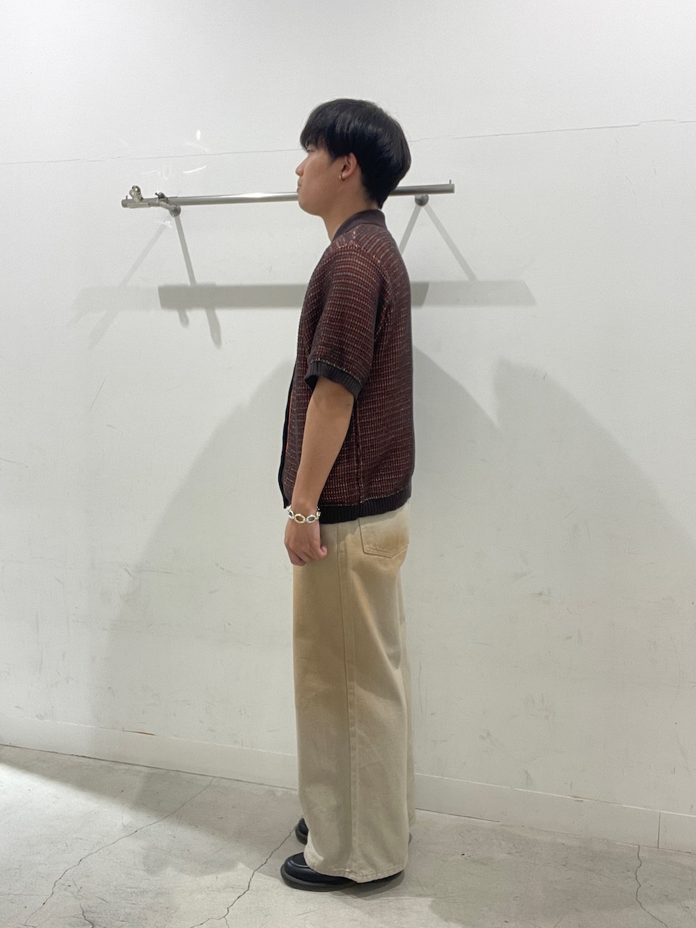 レッド系のニット/セーター、グリーン系のデニムパンツを着用したメンズの春コーディネートの2枚目の写真