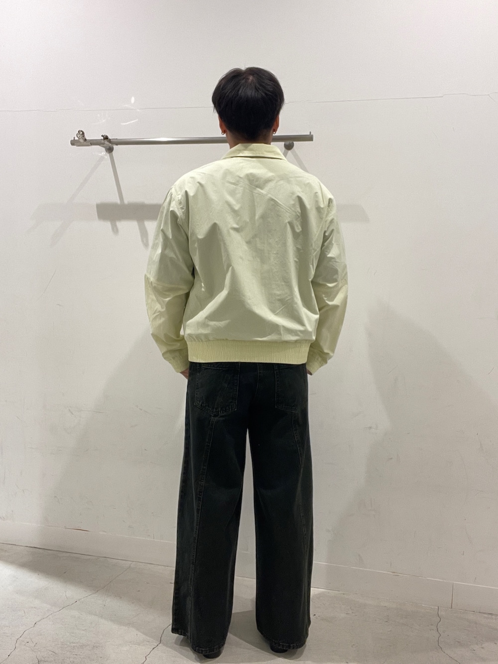 イエロー系のブルゾン、ブルー系のスウェット、ブラック系のデニムパンツを着用したメンズの春コーディネートの3枚目の写真