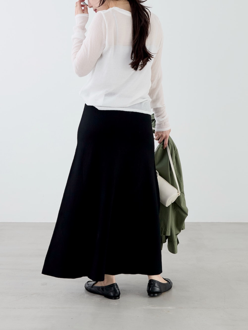 ホワイト系のTシャツ/カットソー、グリーン系のミリタリージャケット、ブラック系のスカートを着用したレディースの秋コーディネートの6枚目の写真