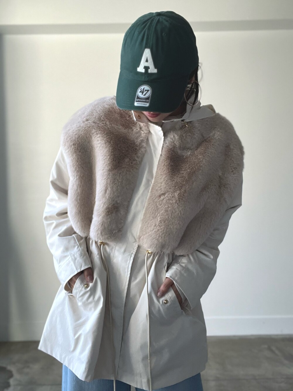 ベージュ系のブルゾン、ブルー系のデニムパンツ、グリーン系のキャップを着用したレディースの秋コーディネートの2枚目の写真