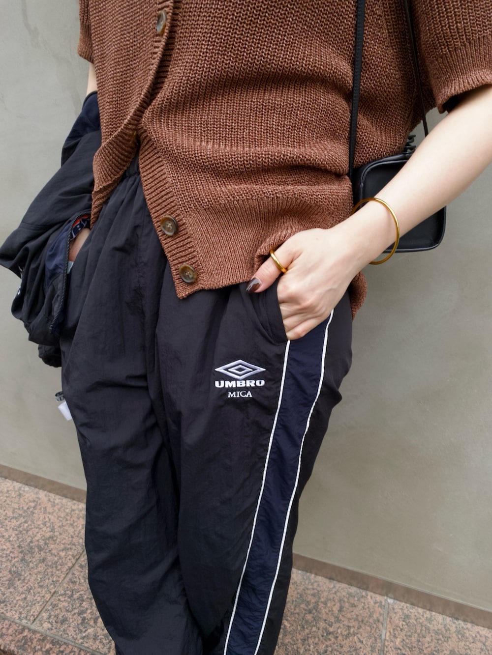ブラウン系のニット/セーター、ブラック系のその他パンツ、ブラック系のブルゾンを着用したレディースの夏コーディネートの4枚目の写真