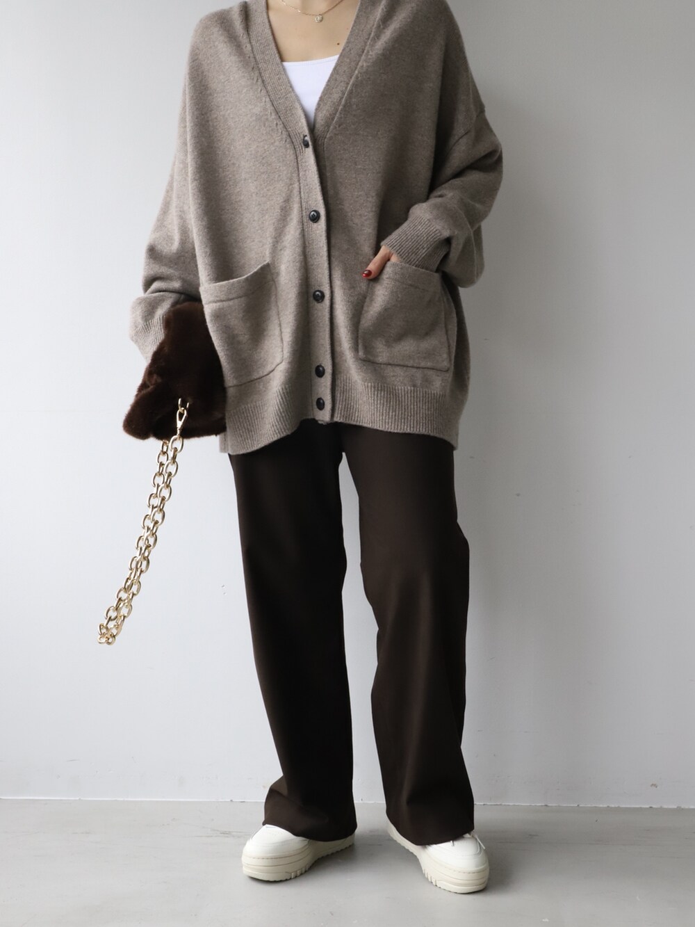 ブラウン系のカーディガン/ボレロ、ブラウン系のその他パンツ、ブラウン系のハンドバッグを着用したレディースの秋コーディネートの4枚目の写真