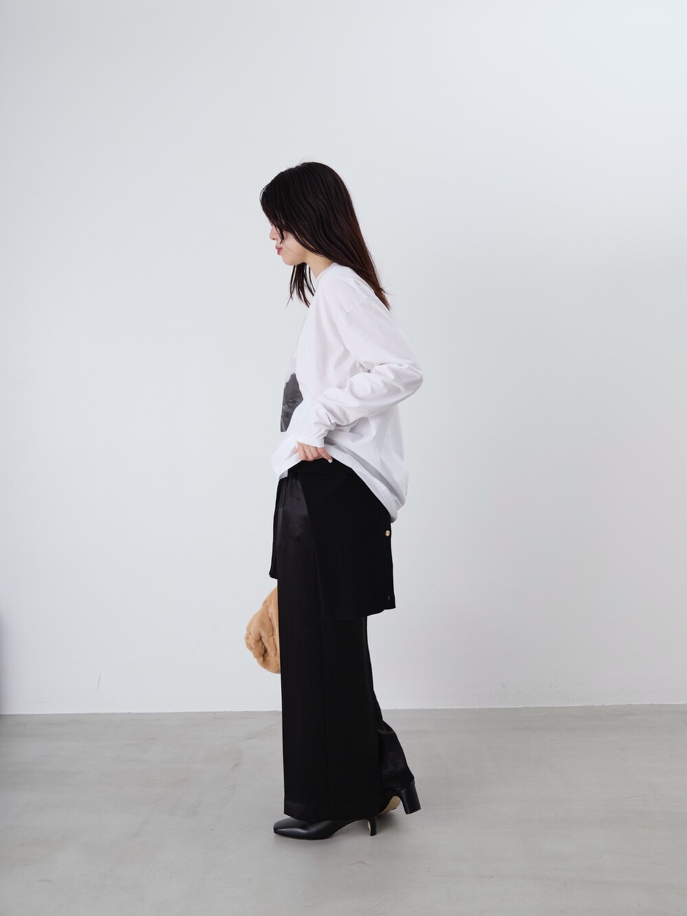 ベージュ系のショルダーバッグ、ホワイト系のTシャツ/カットソー、ブラック系のカーディガン/ボレロを着用したレディースの冬コーディネートの3枚目の写真