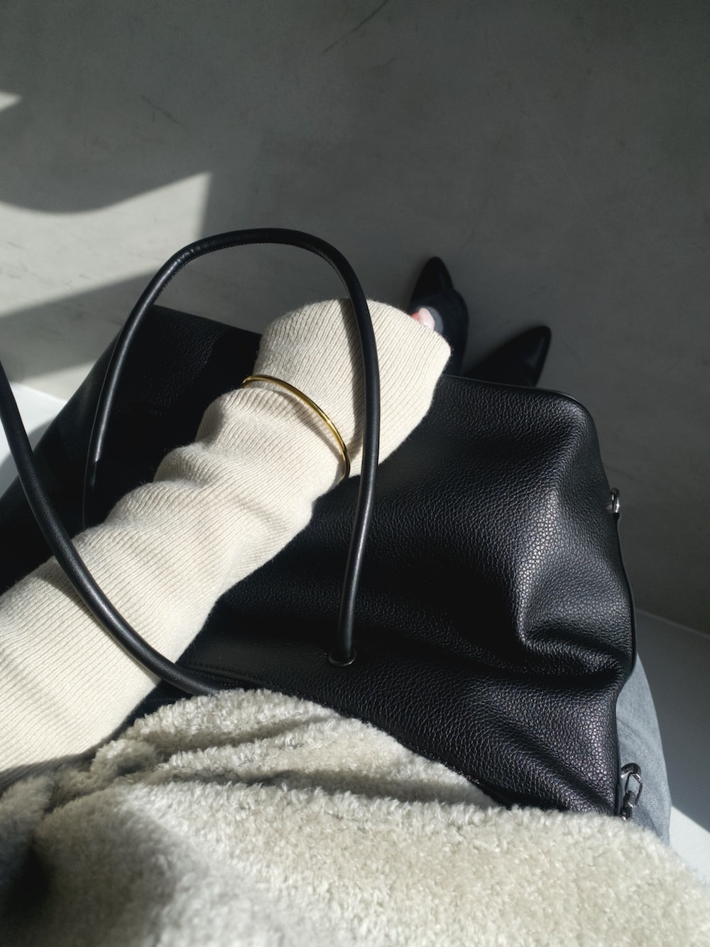 グレー系のニット/セーター、ブラック系のボストンバッグ、グレー系のデニムパンツを着用したレディースの冬コーディネートの5枚目の写真