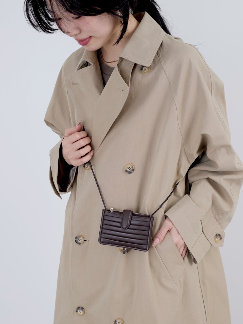 ベージュ系のトレンチコートを着用したレディースの冬コーディネートの3枚目の写真