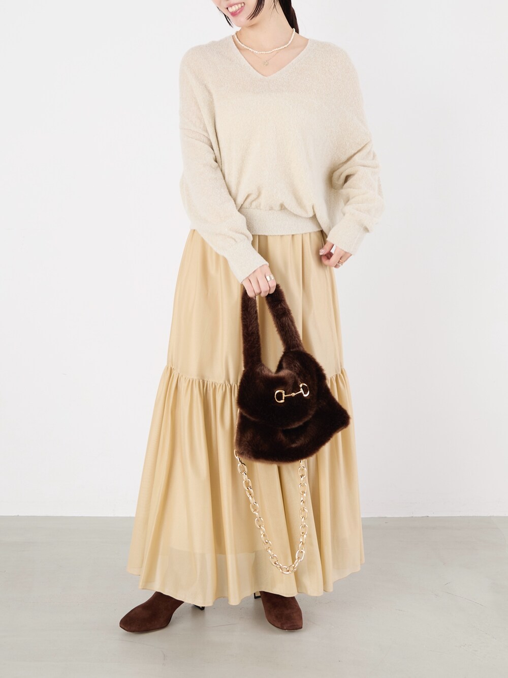 ホワイト系のニット/セーター、ベージュ系のスカート、ブラウン系のハンドバッグを着用したレディースの冬コーディネートの2枚目の写真