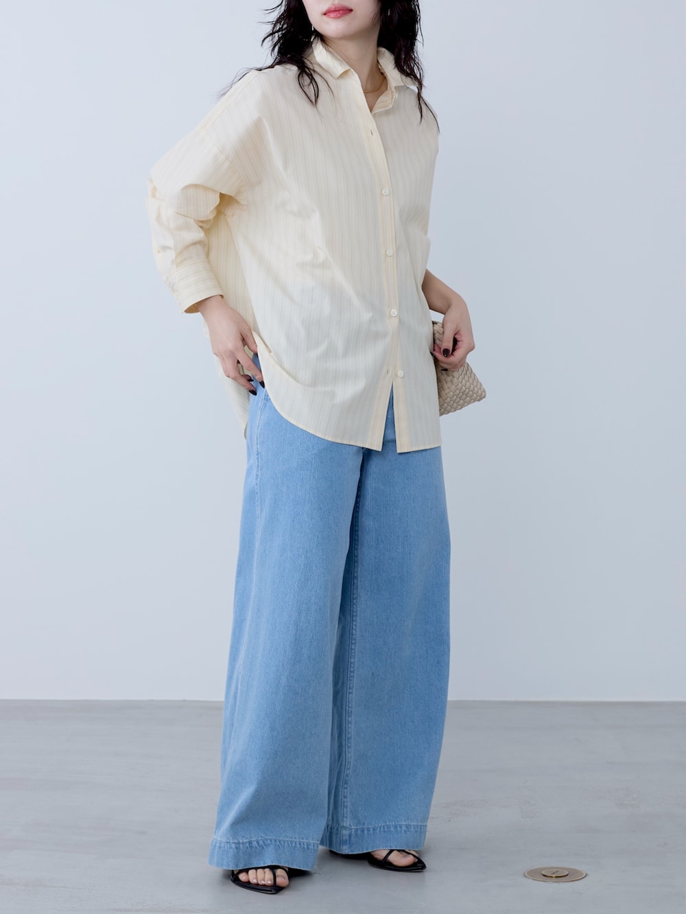 イエロー系のシャツ/ブラウス、ベージュ系のトートバッグ、ブルー系のチノパンツを着用したレディースの冬コーディネートの3枚目の写真