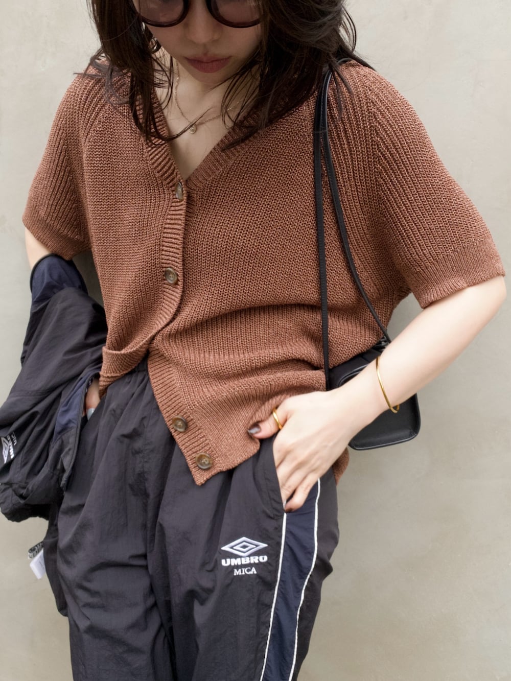 ブラウン系のニット/セーター、ブラック系のその他パンツ、ブラック系のブルゾンを着用したレディースの夏コーディネートの3枚目の写真