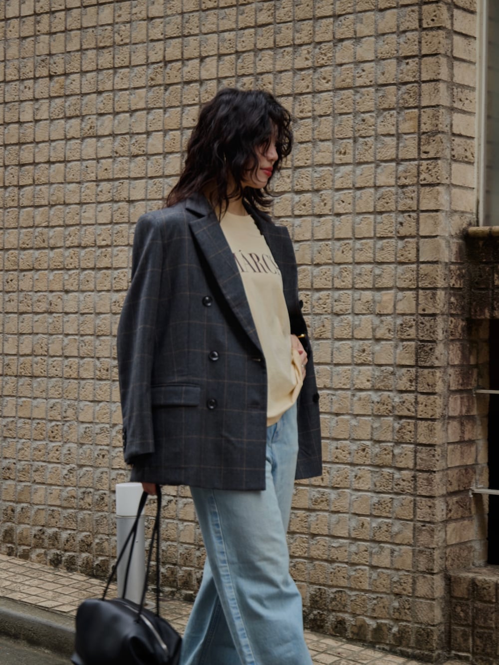 グレー系のテーラードジャケット、オレンジ系のTシャツ/カットソー、ブラック系のボストンバッグを着用したレディースの秋コーディネートの4枚目の写真