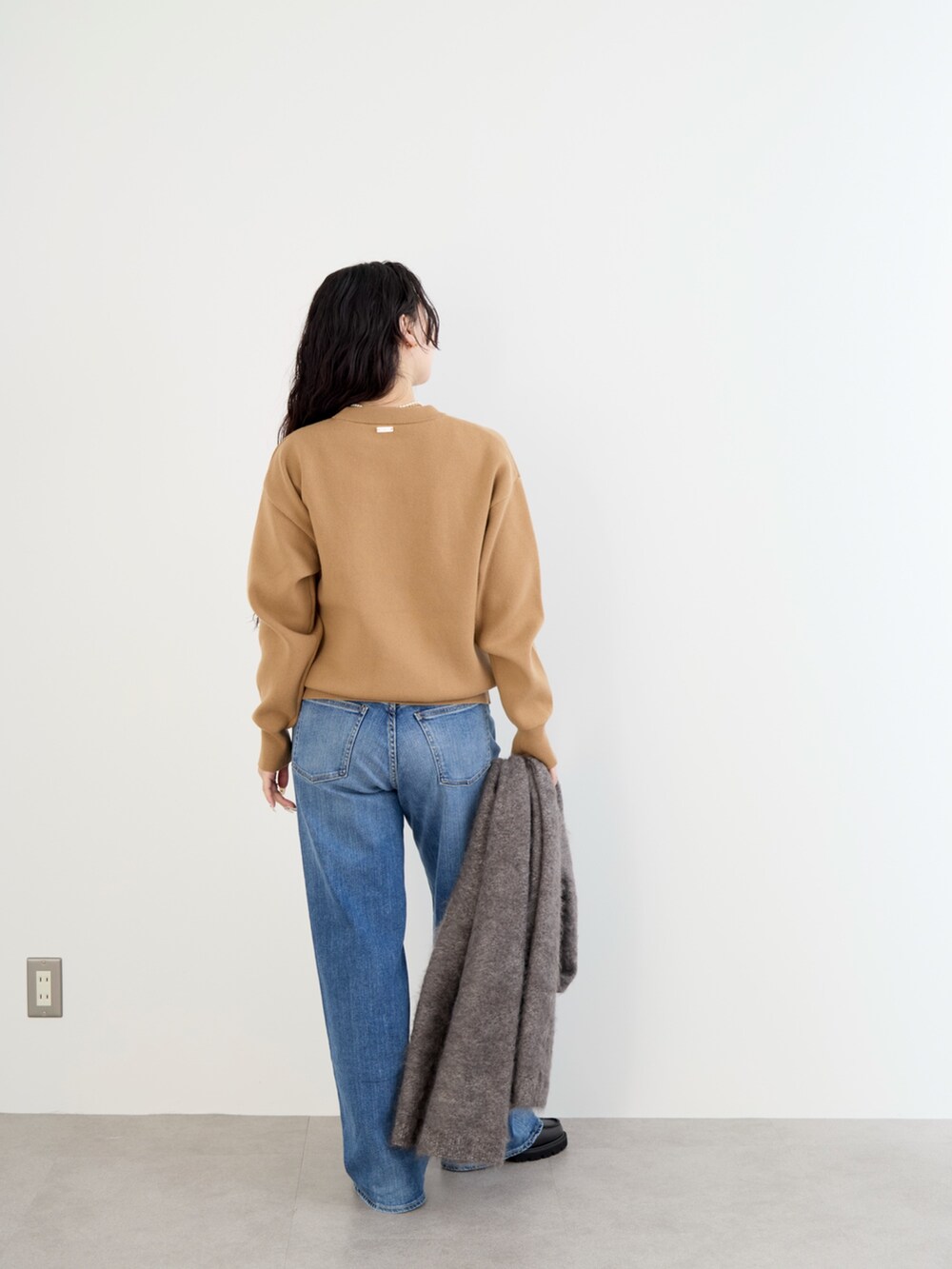 ベージュ系のステンカラーコート、イエロー系のニット/セーター、ブルー系のデニムパンツを着用したレディースの冬コーディネートの10枚目の写真