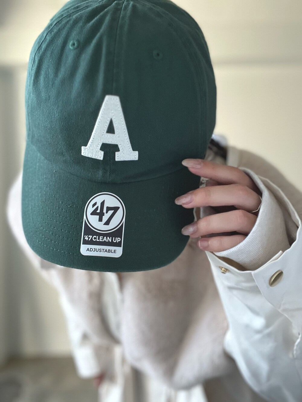 ベージュ系のブルゾン、ブルー系のデニムパンツ、グリーン系のキャップを着用したレディースの秋コーディネートの8枚目の写真